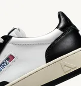 Zapatillas urbanas Autry Medalist Low, de cuero blanco y negro con detalles perforados en la puntera y logo de la marca en el lateral.