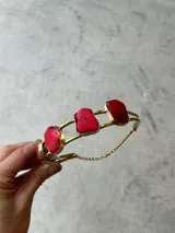 Gargantilla dorada con piedras rojas irregulares y colgante dorado con piedra roja irregular.