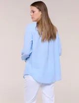 Camisa de lino marca Dash, color beige, con cuello con solapa, escote en V y cierre frontal con botones. Presenta mangas largas regulables con presilla y botón, y un bolsillo aplicado en el pecho.