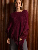 Poncho tejido asimétrico color bordó, con detalle de lentejuelas sutiles y flecos en el ruedo.