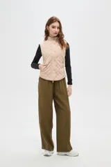 Chaleco negro con diseño capitoneado, cierre frontal con botones a presión y cuello alto.