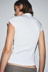 Top negro de tejido de punto, corte ajustado, con cuello alto y mangas sisa caídas.