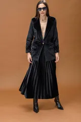 Falda midi plisada de terciopelo negro, con diseño fluido y corte acampanado.