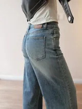 Pantalón de jean con corte wide leg y tiro medio-alto. Presenta un lavado gris azulado desgastado con acabado vintage y ruedo desflecado.