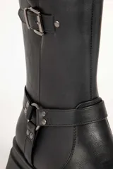 Bota biker negra de símil cuero, con punta redonda y apliques de tachas, hebilla y argolla. Plataforma tractor de 5cm y cierre lateral.