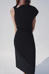 Vestido midi negro de cuello redondo y manga sisa, con detalle de drapeado en la cintura y cierre lateral con cremallera oculta.