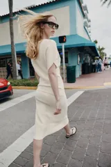 Falda midi de punto color crudo, con tiro medio, cintura elástica y diseño evasé.