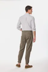 Pantalón de vestir color verde oliva, de corte recto, con bolsillos laterales y traseros. Se ajusta a la cintura con cinturón de cuero marrón.