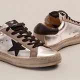 Zapatillas plateadas de cuero vacuno con aplique de estrella en cuero vegetal negro, cordones negros y suela de caucho. El detalle de gamuza es de color gris.