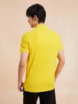 Chomba amarilla de corte slim, con cuello clásico, cartera de dos botones y logo de Tommy Hilfiger bordado en el pecho.