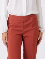 Pantalón sastrero de corte slim, color blanco, con pretina anatómica y panel interno modelador. Presenta bolsillos laterales tipo ojal, bolsillos traseros simulados y nervadura vertical marcada en el frente.