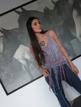 Top tejido artesanal de silueta suelta, con breteles anchos y escote halter. Diseño calado con flecos largos multicolores que aportan movimiento y textura.