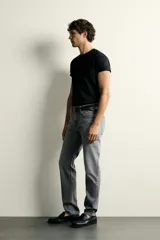Jeans slim fit de color negro para hombre, con tiro medio, diseño de cinco bolsillos y cierre frontal con cremallera y botón.