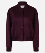 Campera tipo bomber de gamuza sintética color bordó, con cierre frontal de botones a presión, cuello, puños y cintura con tejido acanalado elástico.