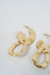 Aros colgantes de diseño moderno con acabado metálico plateado, compuestos por dos piezas irregulares entrelazadas con textura martillada.