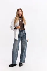 Blusa de algodón en color celeste, con textura sutil, cuello con volados y mangas largas con puños también decorados con volados. Presenta cierre frontal con botones.