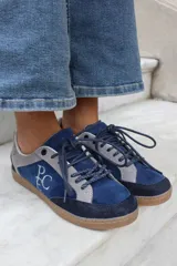 Championes de gamuza en combinación de tonos azul y gris, con suela de goma color caramelo y cordones jaspeados. Presenta el logo bordado en el lateral.