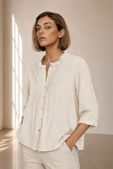 Camisa de lino color beige, con cuello mao con volados, mangas tres cuartos abullonadas y cierre frontal de botones.