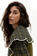 Camisa de algodón con cuello grande tipo babero con volados y terminaciones en encaje. Presenta un estampado de cuadros en tonos marrones y azules, con botones de nácar frontales.