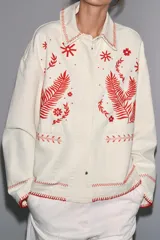 Sobrecamisa color crudo de Zara Woman Collection, con cuello solapa y manga larga. Tiene bolsillos de parche en el delantero y bordados combinados a contraste en color rojo. Cierre frontal con botones a presión ocultos.