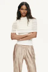 Pantalón wide leg de tejido plisado con ligero brillo, color beige, con cintura elástica y bolsillos laterales.
