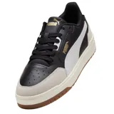 Championes Puma modelo Shuffle Downtown OG, de diseño urbano con base blanca, detalles en negro y suela de goma color caramelo. Presentan refuerzos en gamuza gris en la puntera y el talón, con el logo de la marca en dorado.