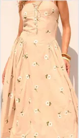 Vestido midi color beige con estampado de flores blancas, breteles finos y escote con cordones.