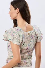 Camisa de lino estampada con diseño floral en tonos lila y verde, mangas cortas con volados y cierre frontal con botones.