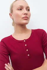 Remera verde de tejido canalé con cuello redondo y media manga. Tiene una abertura frontal con botones.