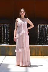 Vestido largo color rosa, con escote halter, corte imperio, falda con volados y espalda descubierta.