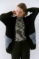 Saco de tejido de punto grueso color negro, con bolsillos frontales de denim.