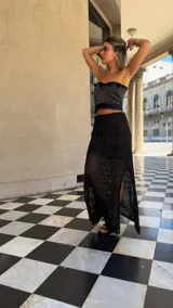 Falda larga negra de tejido red calada con lurex dorado, pretina elástica y tajos laterales. Incluye forro en la zona del caderín.