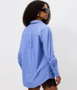 Camisa de manga larga con diseño rayado, cuello inglés y cierre frontal con botones. Confeccionada en tejido de tricolina de algodón, presenta un corte holgado y un bolsillo frontal.