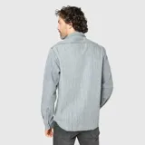 Camisa de denim gris con efecto lavado, manga larga, cuello clásico y dos bolsillos frontales con solapa.