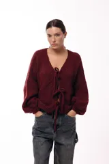 Saco tejido de punto color bordó, con escote en V y cierre frontal mediante lazos. Presenta mangas largas amplias con puños ajustados y un calce relajado.