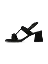 Sandalias de tacón ancho color negro con tiras cruzadas y apliques de botones metálicos dorados en la parte central. Tira ajustable al tobillo con hebilla dorada.