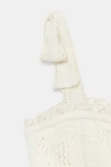 Top de punto color crema con escote recto, tirantes anchos con lazos decorativos, cintura elástica y terminaciones con puntilla.