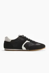 Calzado deportivo con diseño de bloques de color en negro y blanco, con cordones, collarín acolchado y suela de goma.