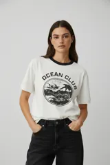 Remera de algodón color blanco con cuello redondo en contraste negro y estampado frontal circular con la leyenda Ocean Club.