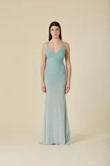 Vestido largo de tul color verde agua, con escote en V, tirantes dobles finos y detalles de pedrería brillante distribuida por toda la prenda. Presenta una silueta ajustada en el torso que se abre suavemente hacia el ruedo.