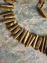 Collar corto de piedras naturales en bruto en tonos dorados y azules, con cadena de eslabones y cierre ajustable metálicos.