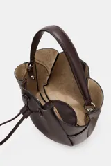 Bolso de mano tipo saco mini, color marrón oscuro, con detalle de pespuntes en el cuerpo y cierre mediante botón imantado. Incluye tira ajustable frontal y compartimento interior con cremallera.