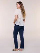 Blusa de estilo romántico color beige confeccionada en algodón, con escote amplio, importante volante capa en broderie calado, cartera frontal con botones tipo perla, bordados verticales calados, cintura marcada con bajo peplum y ruedo recto festonado.