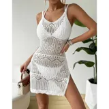 Vestido de playa blanco corto y sin mangas, confeccionado en poliéster con diseño calado de tejido a crochet, cuello redondo y tajo lateral.