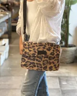 Bandolera rectangular con solapa, confeccionada en cuero con estampado animal print de leopardo. Presenta correa larga de cuero ajustable y herrajes metálicos.