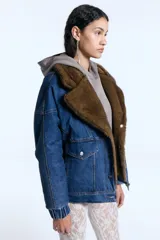 Campera reversible de denim azul con interior de piel sintética marrón. Presenta cuello solapa amplio, cierre frontal con botones metálicos, bolsillos con solapa y puños elásticos.
