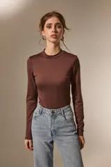 Body de manga larga con cuello a la base, confeccionado en poliamida, con ajuste al cuerpo y cierre inferior con broches.