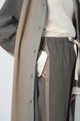 Tapado largo marrón con diseño texturizado, cuello camisero, abotonadura frontal y tajos laterales.