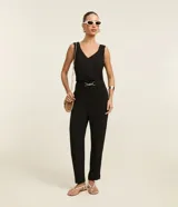 Pantalón negro de corte zanahoria, con cintura elástica, adorno metalizado en la cintura y bolsillos laterales.