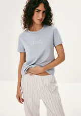 Pijama compuesto por una remera de manga corta color celeste con estampa frontal y un pantalón largo de corte recto con estampado de rayas verticales en tonos neutros.